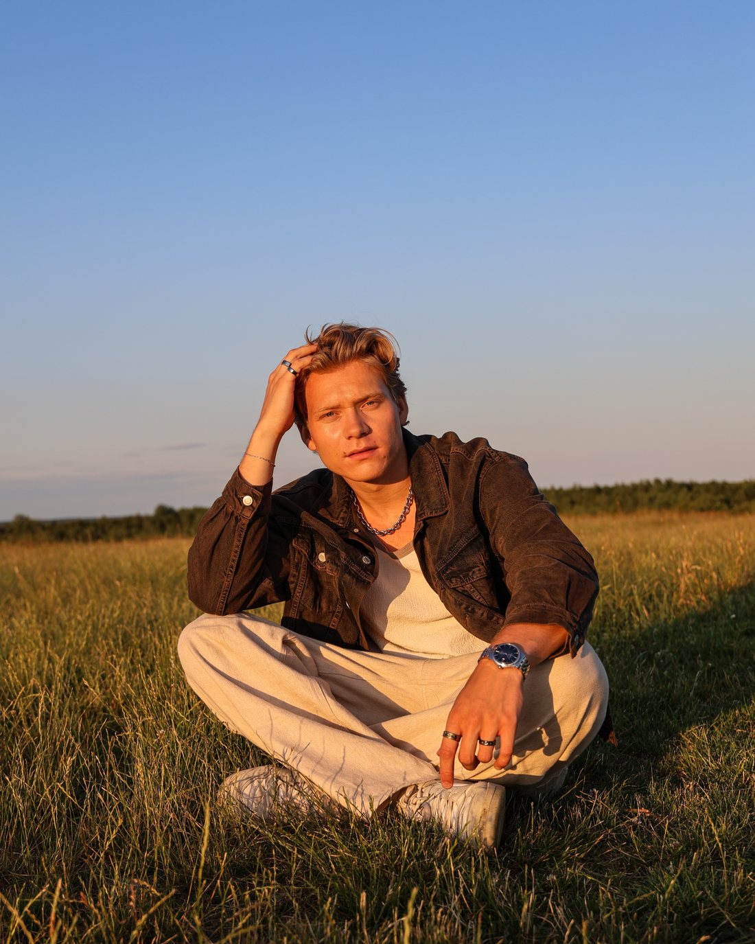 Adam Woods sitting in a summer field at golden hour