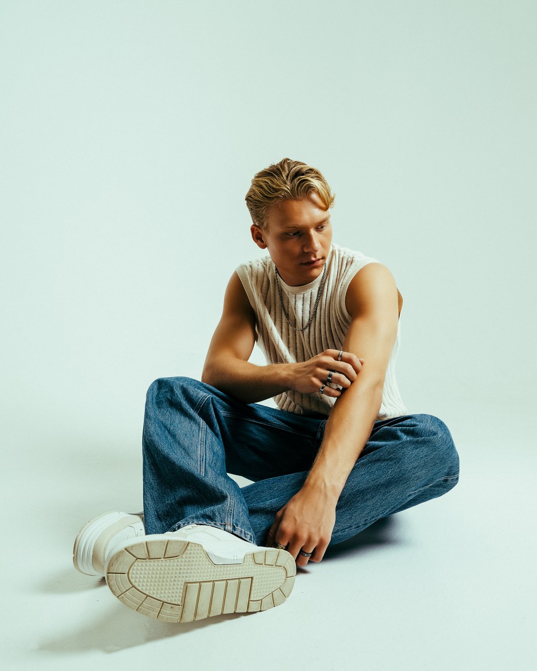 Adam Woods sitting cross-legged against a pale studio backdrop