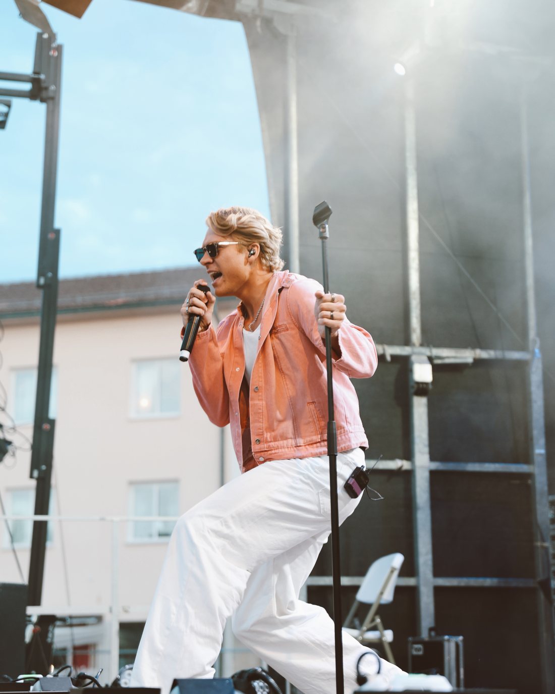 Adam Woods singing into a handheld microphone on an outdoor festival stage